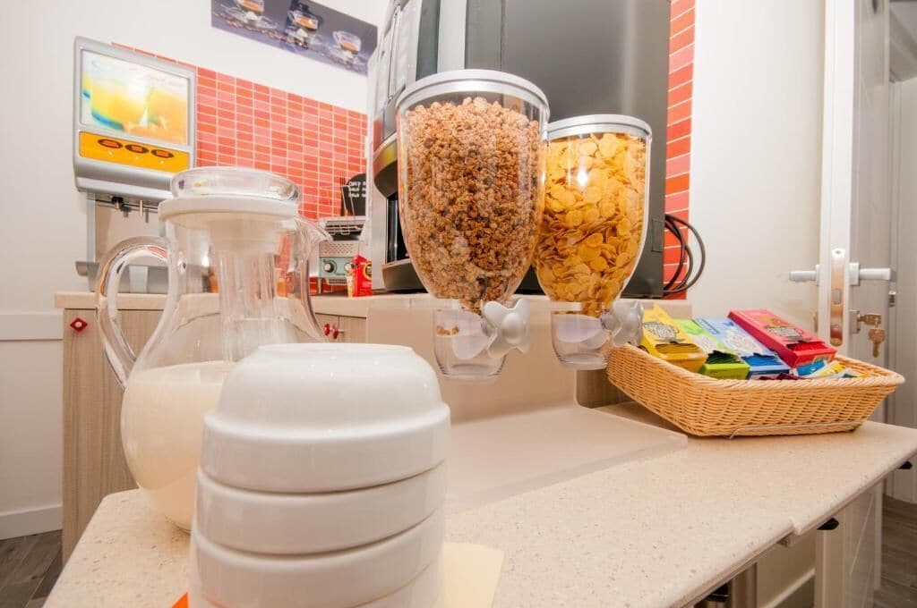 Un plan de travail de cuisine avec un pichet de lait, un mixeur et un panier rempli de boîtes de céréales.