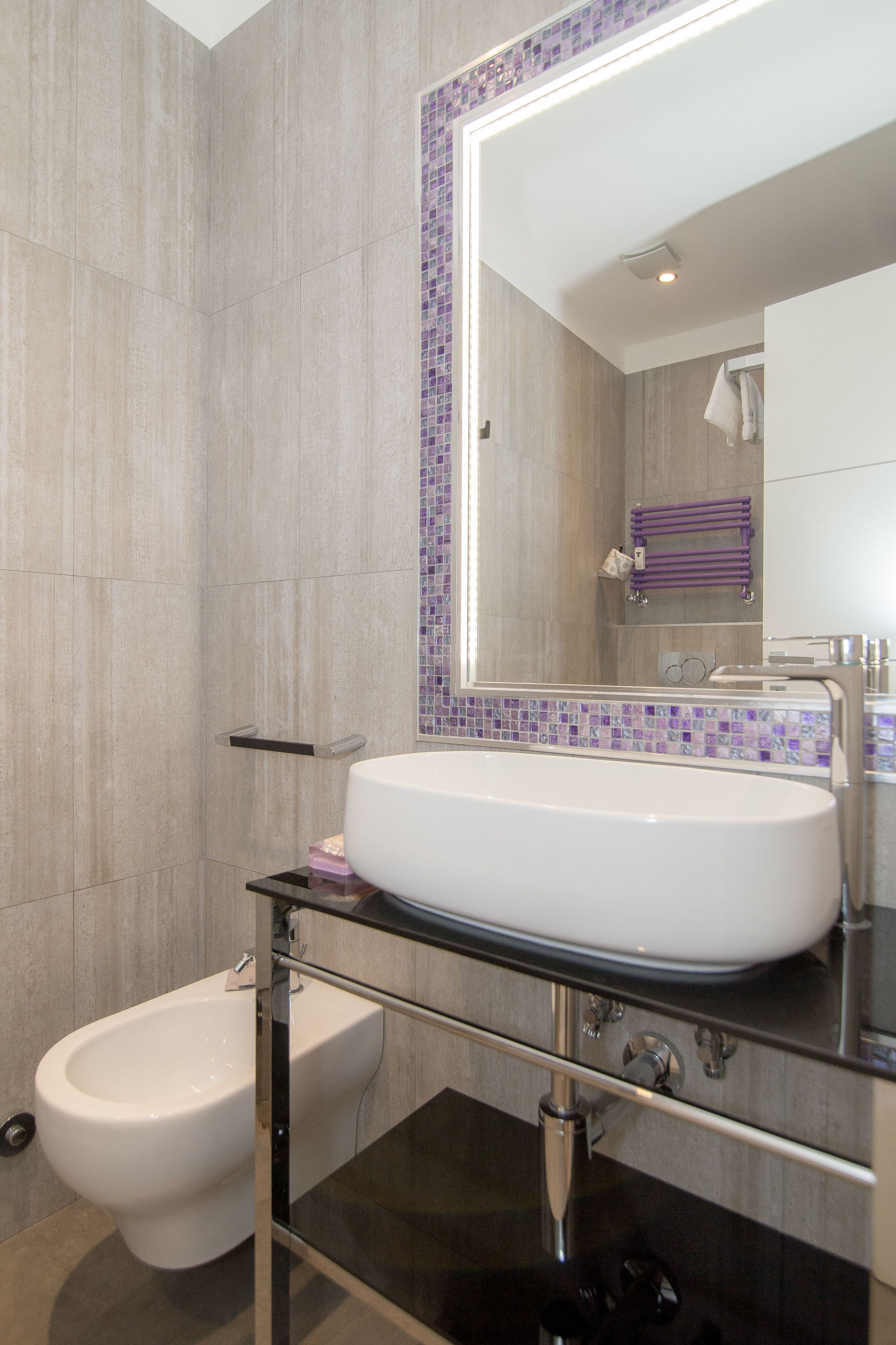 A modern bathroom with a large mirror, a bidet, and a glass-enclosed sink.
