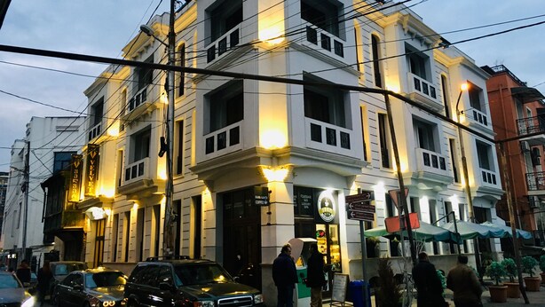 Un edificio de varios pisos con un estilo arquitectónico clásico, que cuenta con una cafetería en la planta baja y un letrero visible de un spa de lujo.