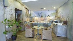 Una cocina moderna con una isla central, dos sillas acolchadas, una planta en maceta y un mural en la pared.