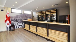 Zona de bar con bancos de madera, una barra y una bandera.