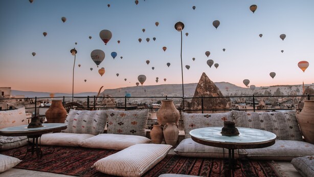 A rooftop terrace with traditional cushions, a round table, and multiple clay pots. - Taskonak Hotel (Nevsehir)