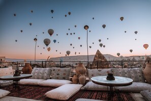 A rooftop terrace with traditional cushions, a round table, and multiple clay pots. - Taskonak Hotel (Nevsehir)