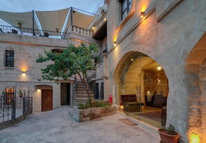 A courtyard with stone walls, a wooden door, and a staircase leading to an upper level. - Taskonak Hotel (Nevsehir)