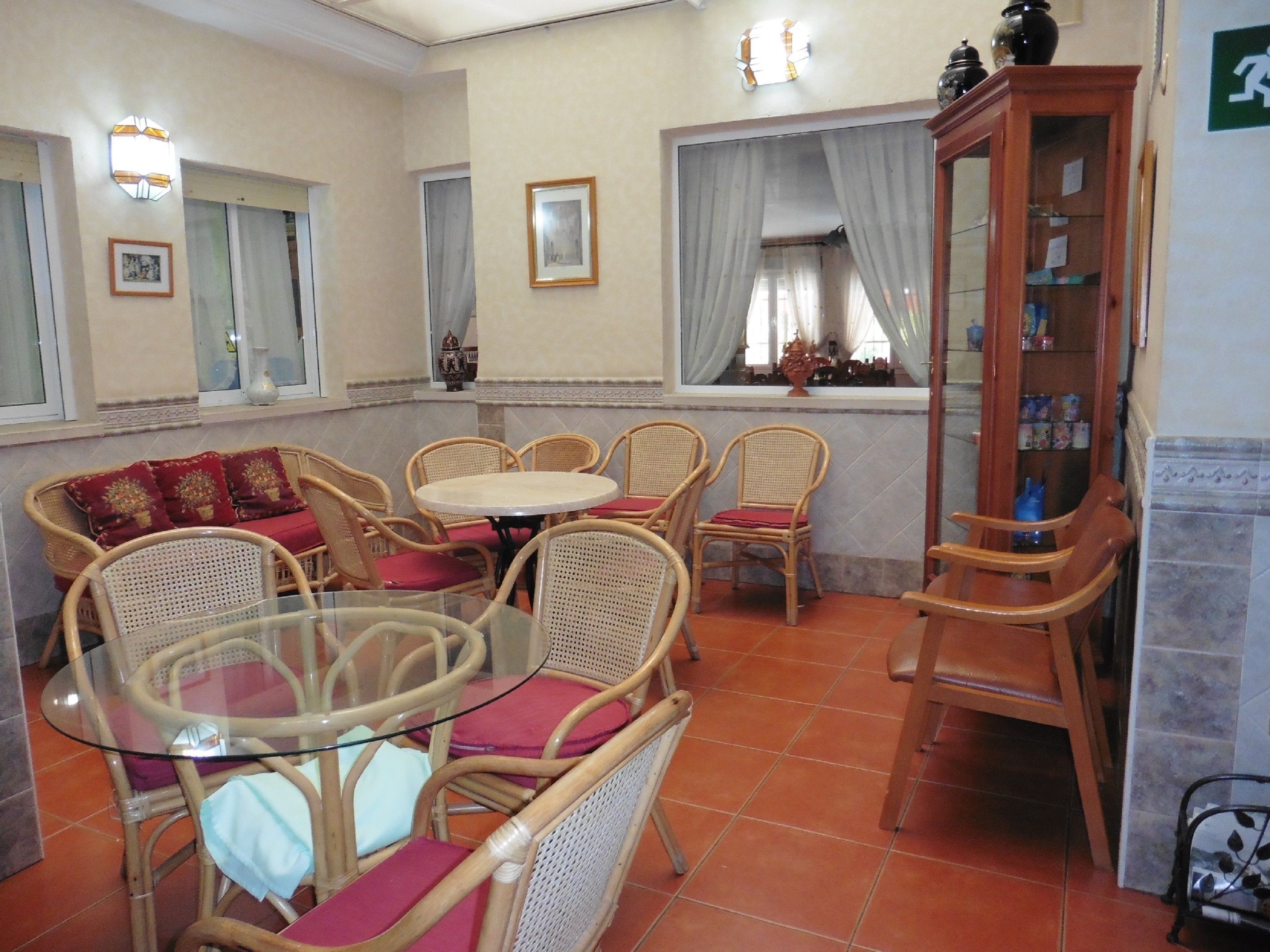 A dining area with wicker furniture, a glass table, and a wooden cabinet with glass doors.