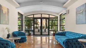 A lobby with a curved ceiling, a blue sofa, a small table, and a large glass door leading outside.