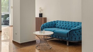 Un vestíbulo moderno con un sofá azul, una mesa redonda y una planta en maceta.