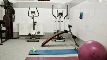 A gym with exercise equipment, a blue mat, and a pink exercise ball.