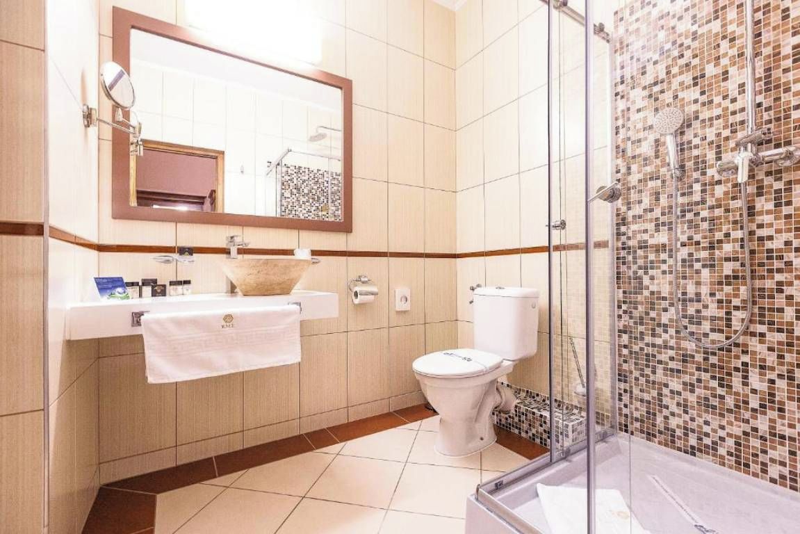 Un baño con lavamanos, espejo, inodoro y zona de ducha.
