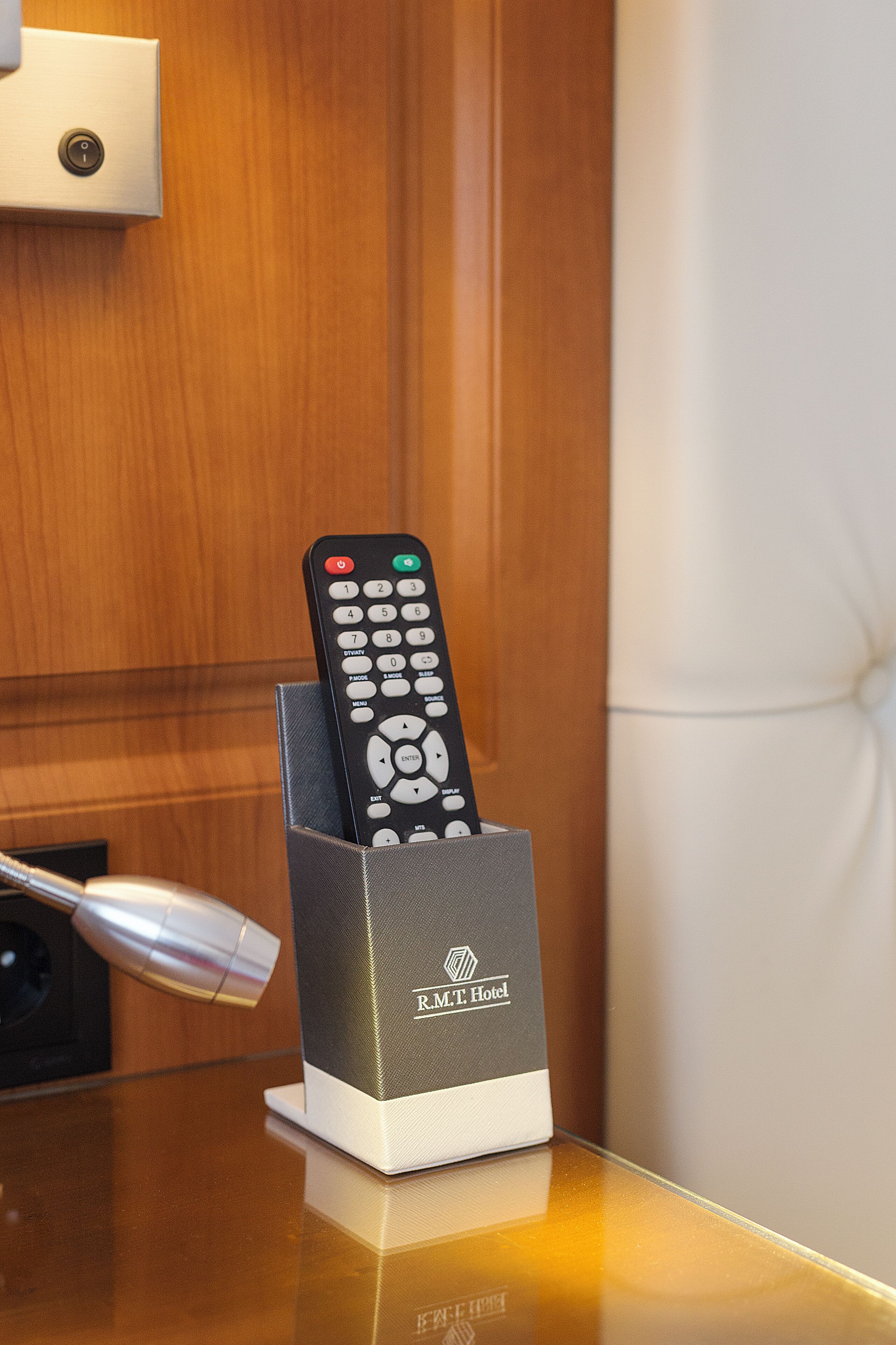 A remote control in a holder on a table with a wooden background.