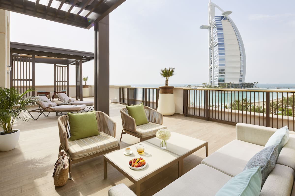 En takterrass med utomhusmöbler, utsikt över Burj Al Arab och en krukväxt.