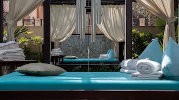 Relax in a serene outdoor lounge with a comfortable sofa, curtains, and lush greenery.