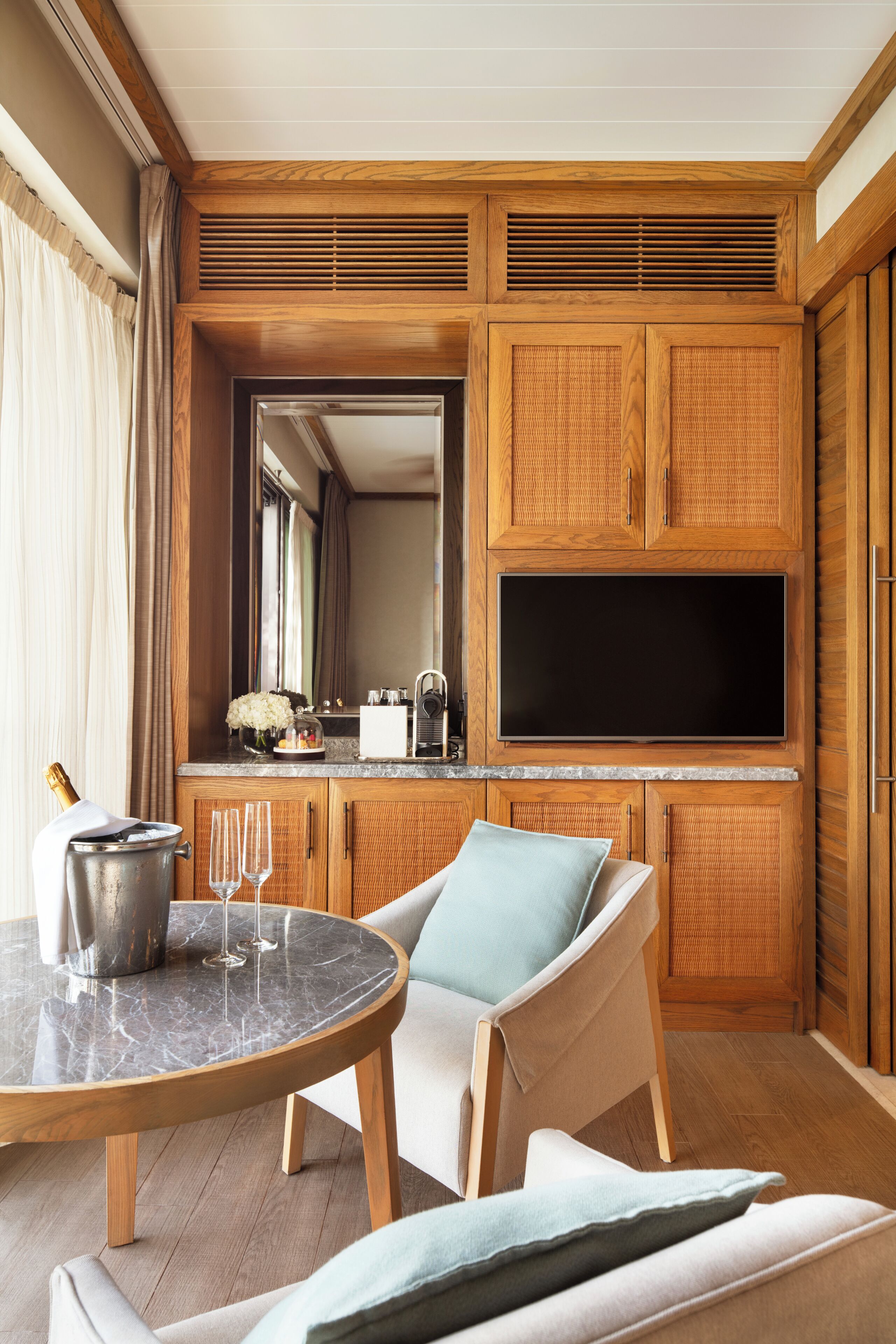 A modern kitchen with wooden cabinetry, a flat-screen TV, and a dining area with a round table and chairs.