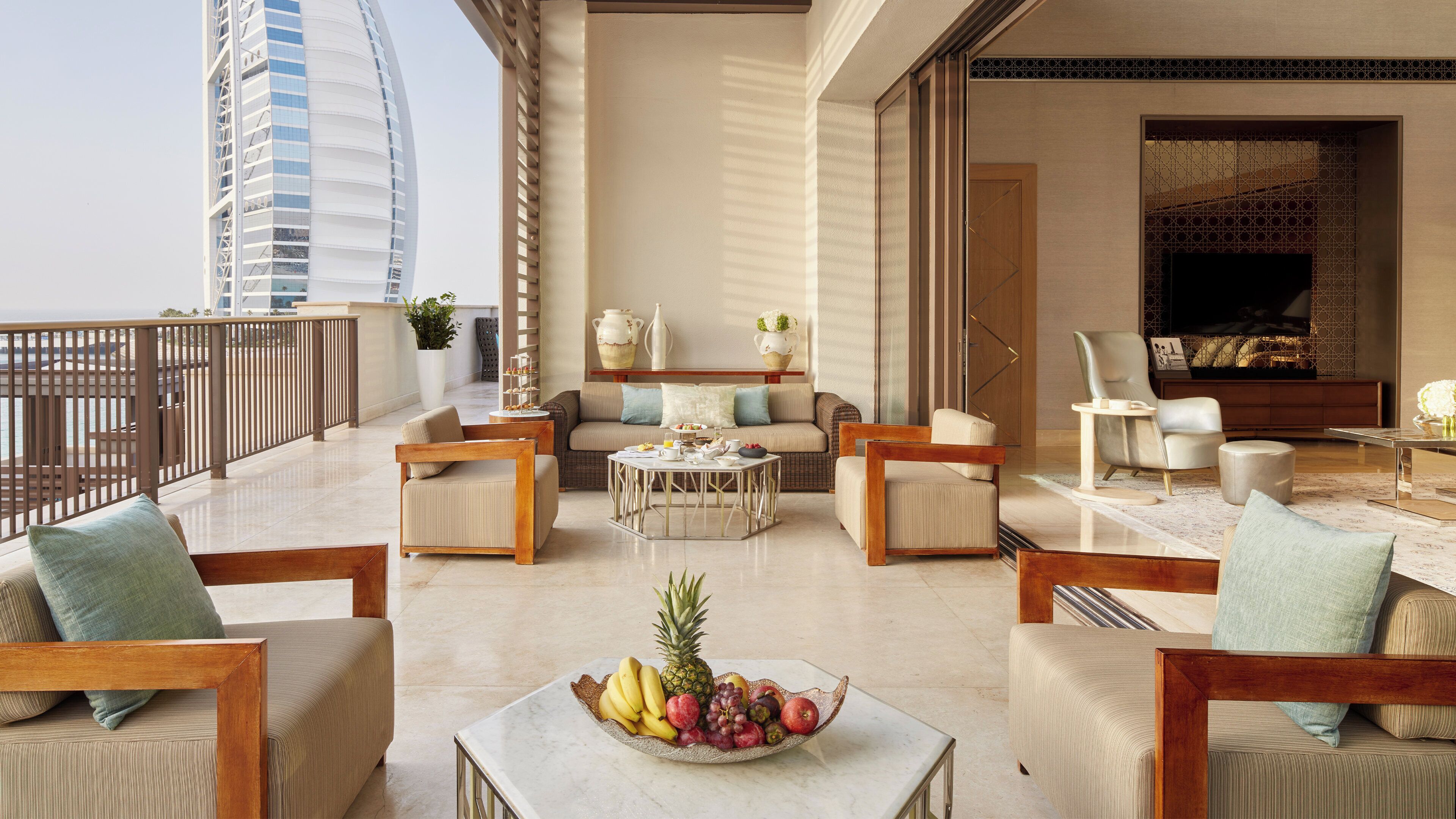 Ein geräumiger Balkon mit Blick auf ein hohes Gebäude, ausgestattet mit Sofas, einem Couchtisch und einer Obstschale.