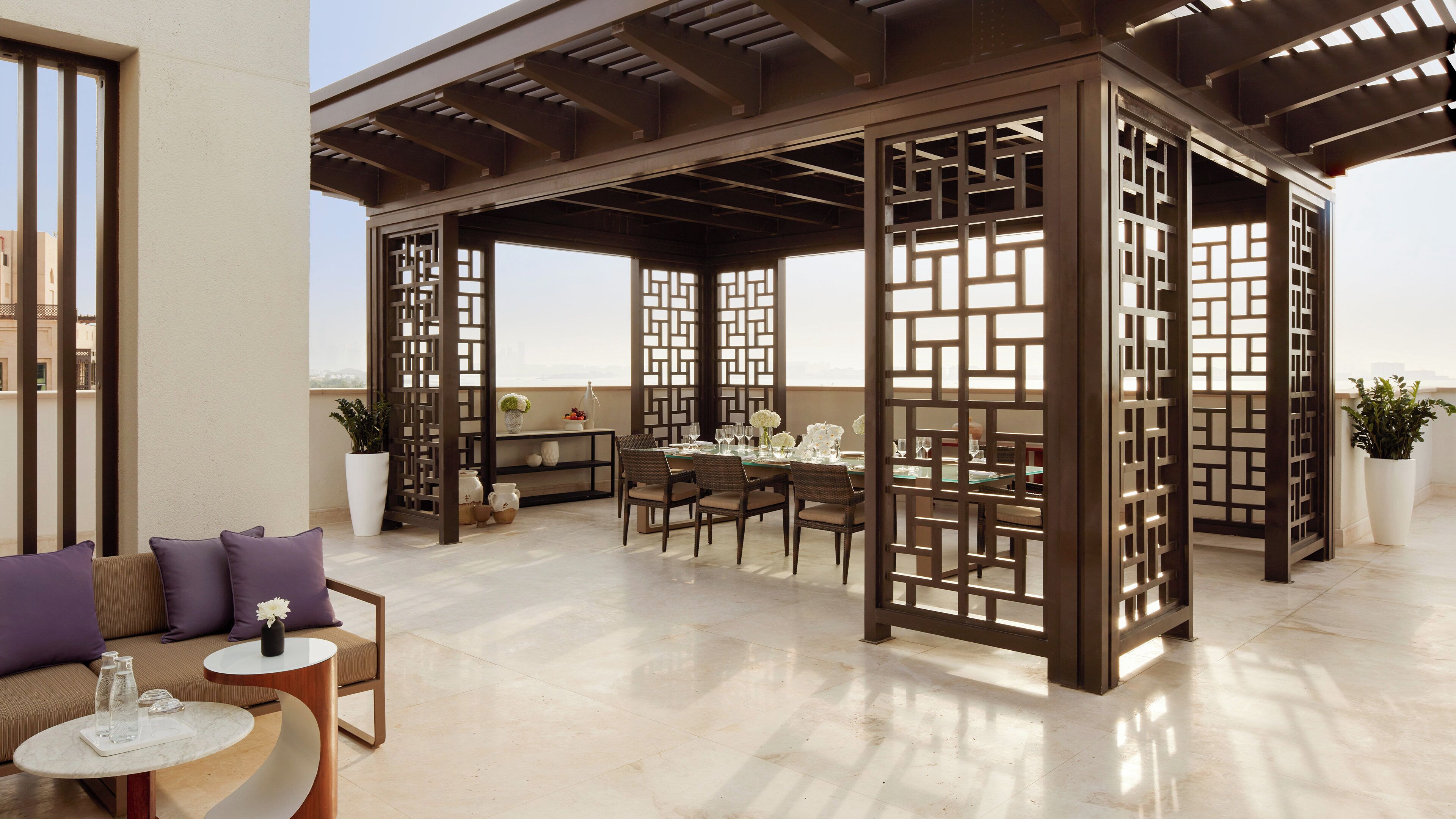 Eine großzügige Außenpatio mit Essbereich, gepolsterten Sitzgelegenheiten und einer Pergola.