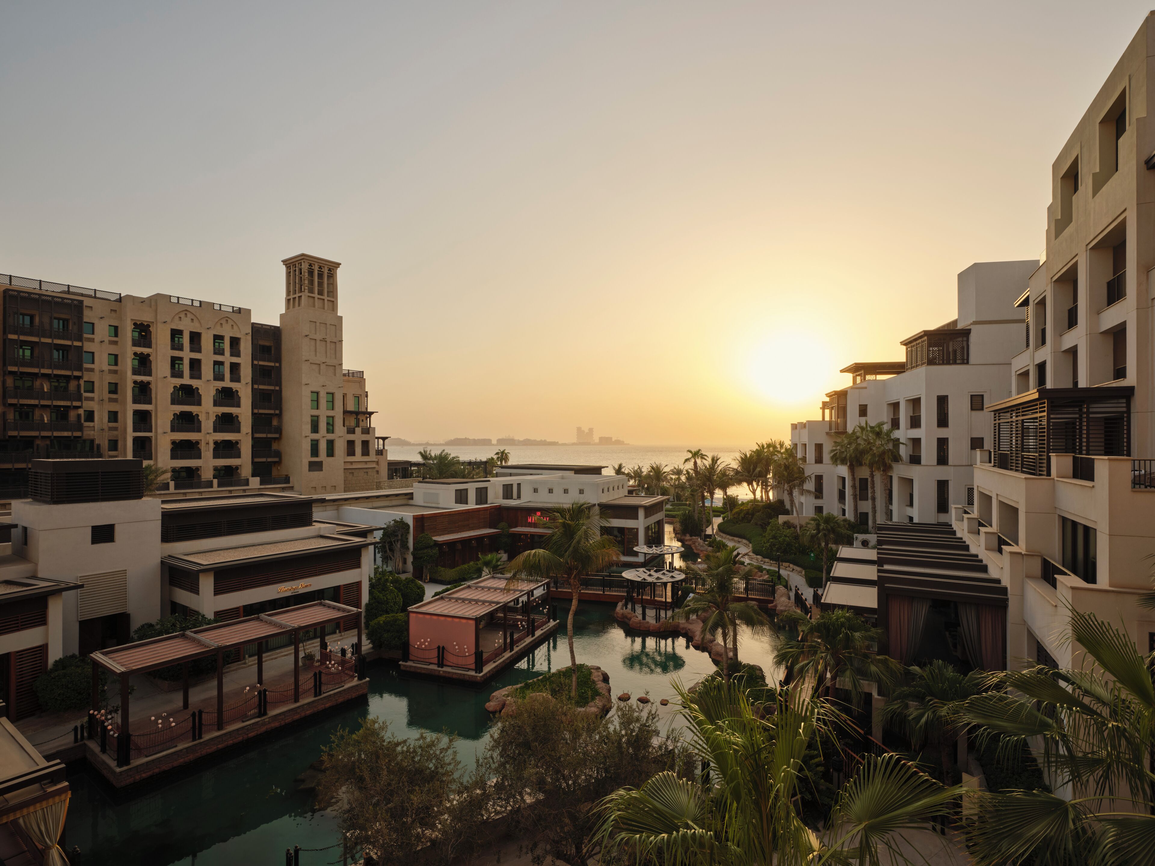 Un resort con piscina, palmeras y edificios con balcones.