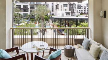 Un balcone con vista su un complesso di edifici moderni, un tavolo rotondo con sedie e un divano con cuscini.