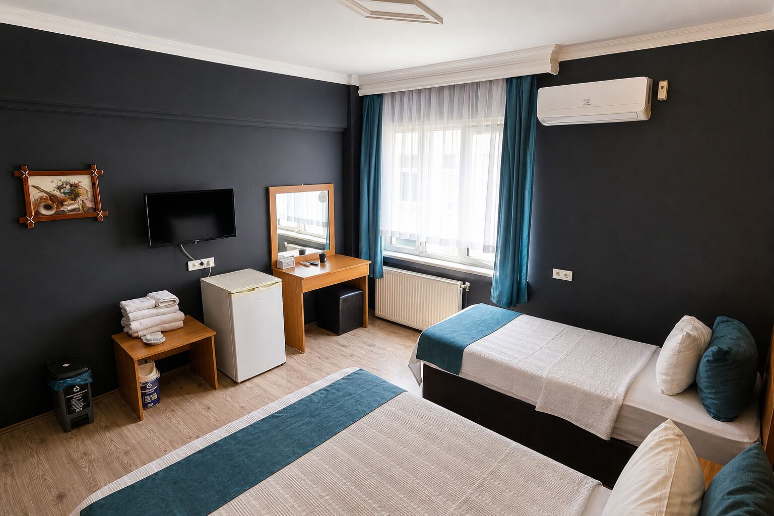 Een hotelkamer met een bed, een bureau, een televisie, een spiegel en een raam met gordijnen.