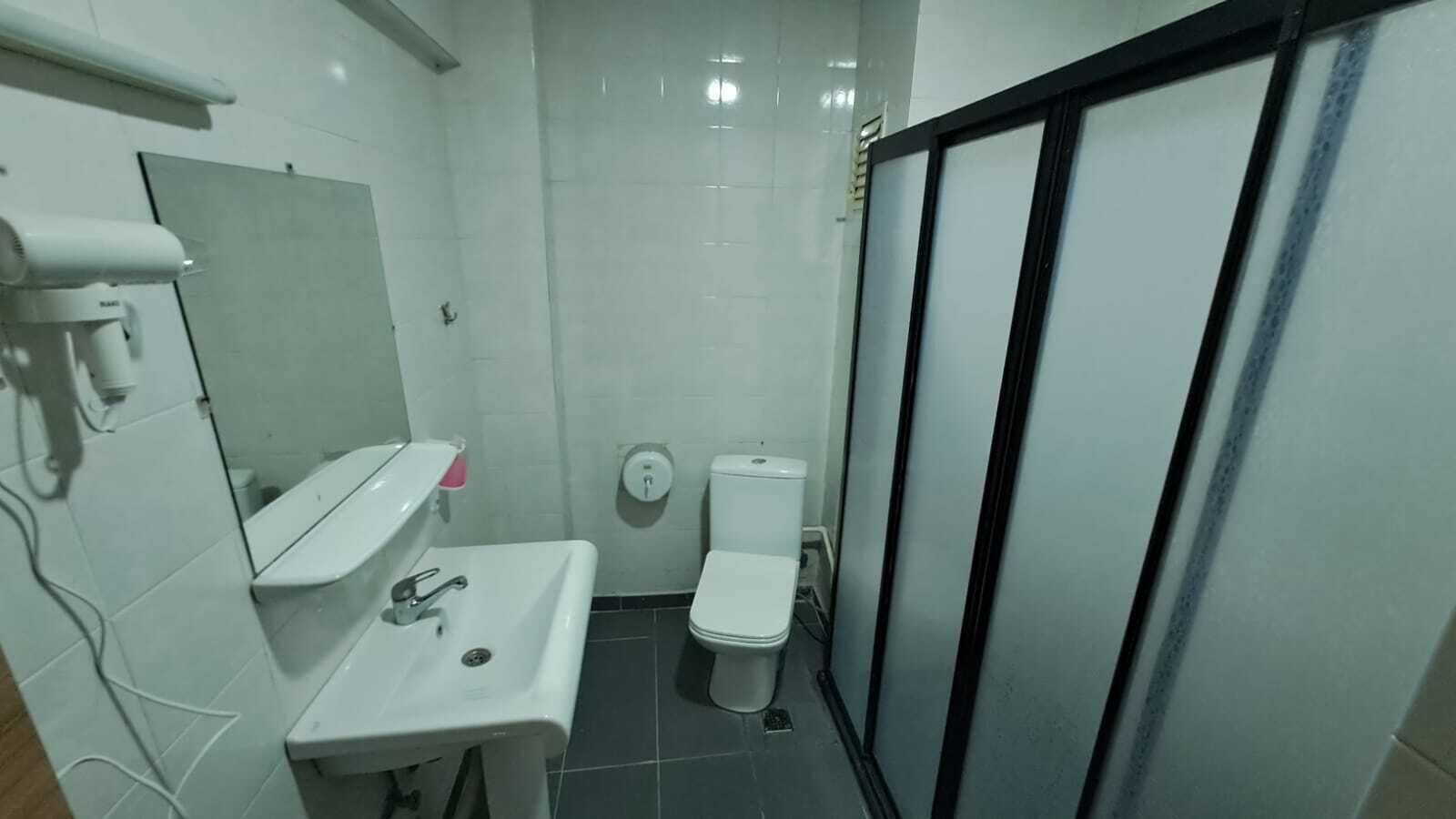 A small, clean bathroom with a white sink, mirror, and toilet.