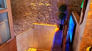 Un escalier avec un mur en briques, une petite plante et un présentoir éclairé en bleu.