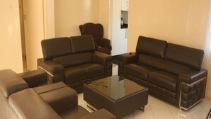 Een moderne woonkamer met een modulaire bank, een glazen salontafel en een fauteuil.