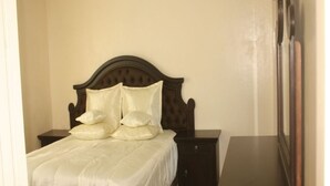 Een slaapkamer met een bed, twee nachtkastjes, een dressoir en een spiegel.