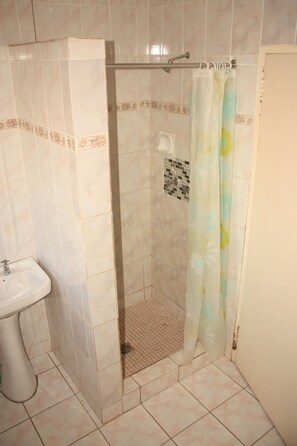 A bathroom with a shower, a sink, and a tiled floor.