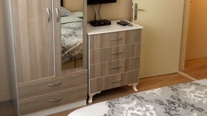 Une chambre à coucher comprenant une armoire, une commode, un lit et un téléviseur.