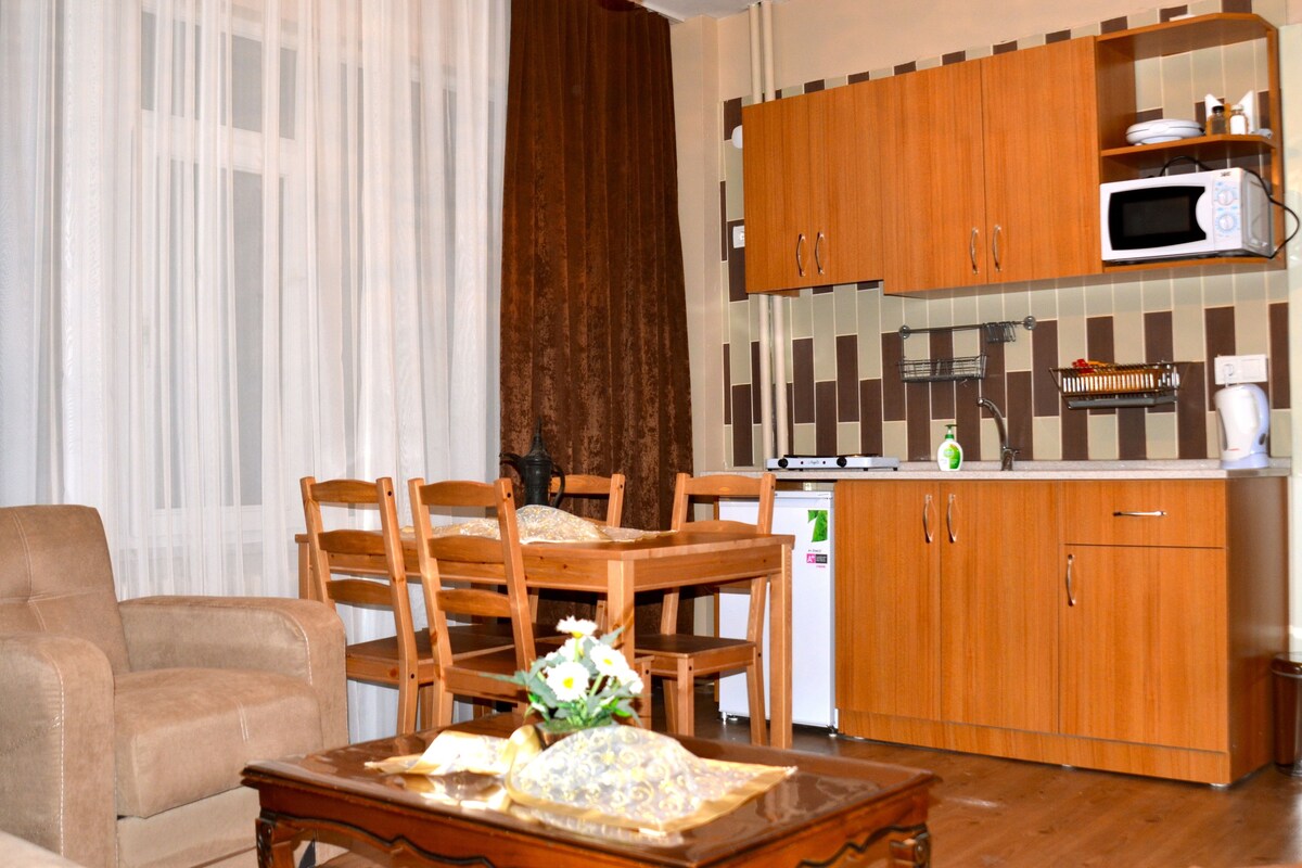 A compact living space with a dining area, a kitchenette, and a sofa.