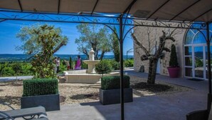 Een terras buiten met uitzicht op zee, met een pergola, potplanten en een zithoek.