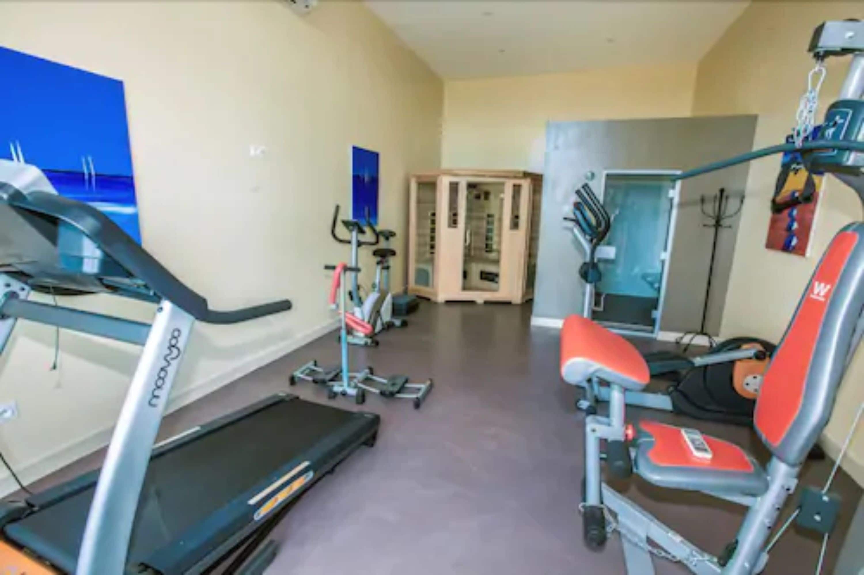 Una palestra con attrezzature cardio, macchinari per pesi e uno specchio.