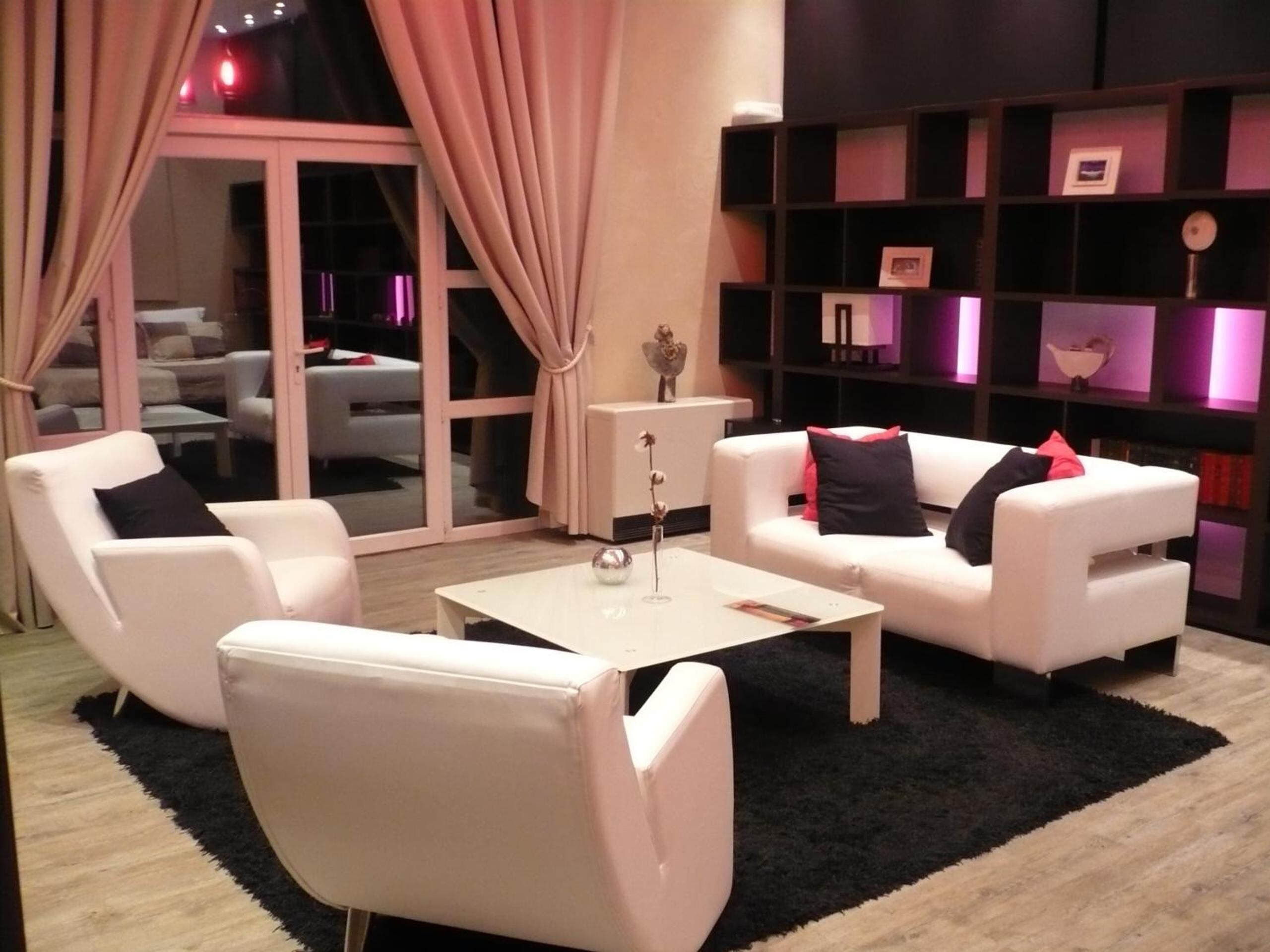 A modern living room with white sofas, a coffee table, and a bookshelf.