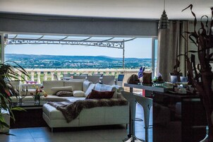 Una sala de estar con sofá, mesa de centro y vista a un paisaje urbano a través de un ventanal grande.
