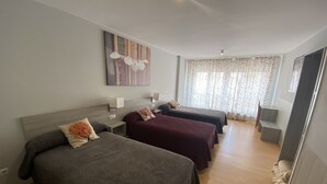 A hotel room with two beds, a wooden headboard, a painting, a window with curtains, and a small table with a lamp. - Hostal DP Cristal (Sarria)