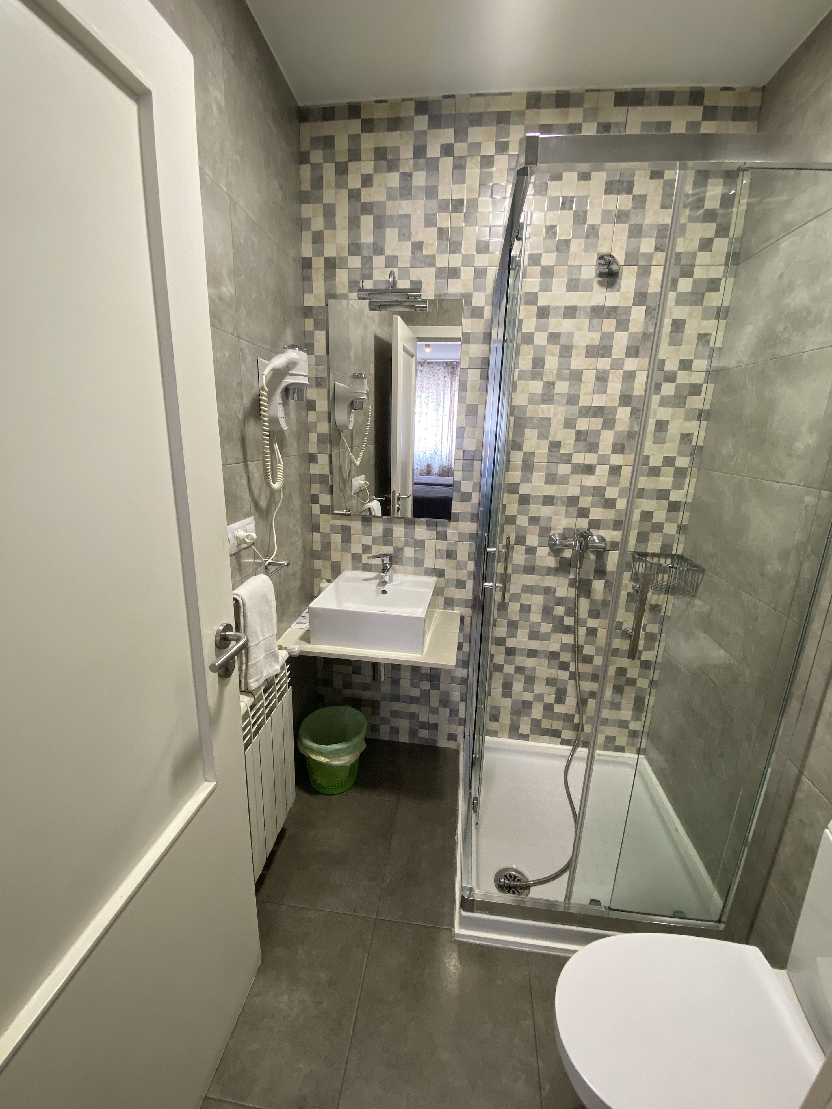 Een badkamer met een glazen douchecabine, een wastafel en een toilet.
