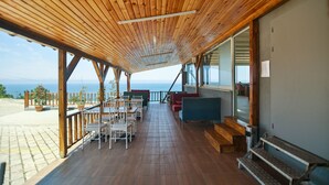A wooden deck with outdoor seating, a view of the sea, and a staircase leading to an upper level. - Diamond Hotel (Amasra)