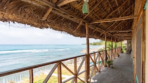 A covered walkway with a view of the ocean, wooden railings, and potted plants. - Yoset Hotel (Cayes-Jacmel)