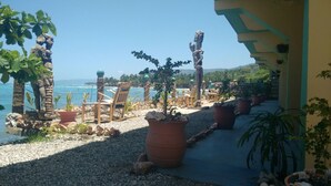 A patio area with outdoor seating, potted plants, and a view of the ocean. - Yoset Hotel (Cayes-Jacmel)