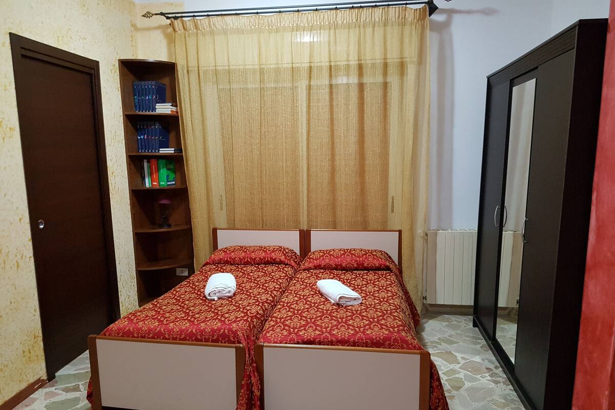 A bedroom with a double bed, a bookshelf, and a wardrobe.