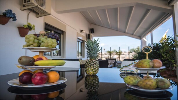 Una exhibición de frutas con diferentes tipos de frutas en estantes escalonados, un piña como pieza central y vista al exterior.