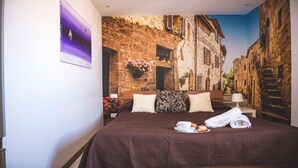 Un dormitorio con cama, almohadas, una mesita de noche, una lámpara y un cuadro en la pared.