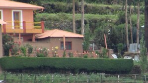 Un edificio de dos pisos con balcón, rodeado de exuberante follaje y un jardín bien cuidado.