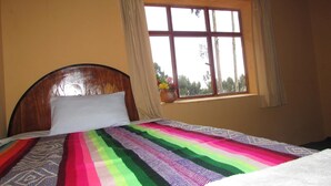 Una cama con un colorido edredón a rayas, un cabecero de madera y una ventana con cortinas.