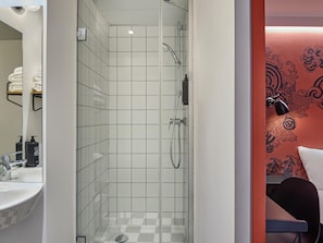 A modern bathroom with a glass-enclosed shower, a white sink, and a mirror. - Ibis Styles Paris Gare de l'Est Magenta (Paris)