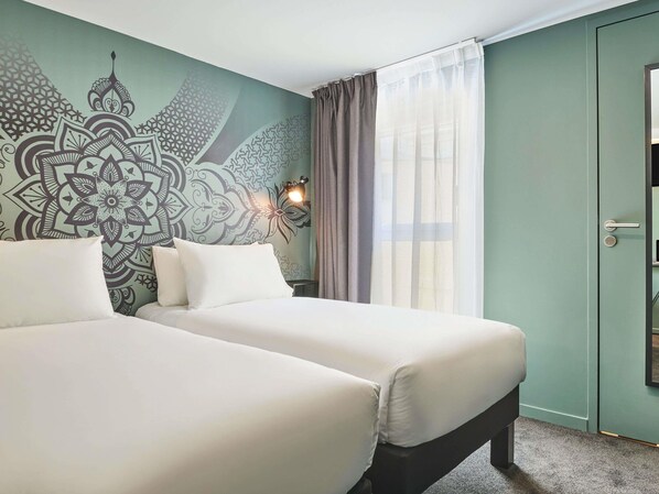 A hotel room with two beds, a patterned wall, a window with curtains, and a door. - Ibis Styles Paris Gare de l'Est Magenta (Paris)