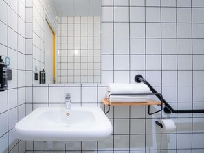 A bathroom with a white sink, a mirror, a towel rack, and a toilet paper holder. - Ibis Styles Paris Gare de l'Est Magenta (Paris)