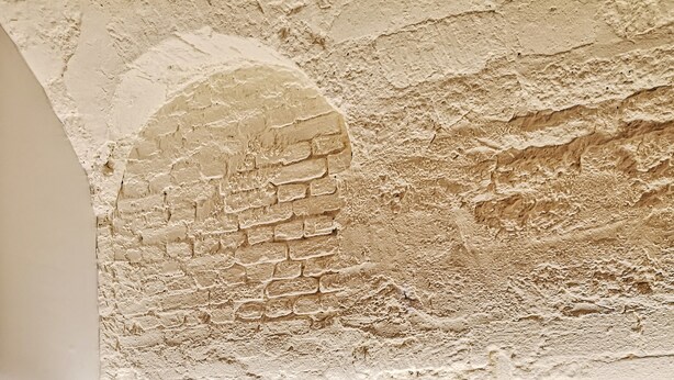 Interior de restaurante con pared de ladrillo, paneles de madera y suelo a cuadros.