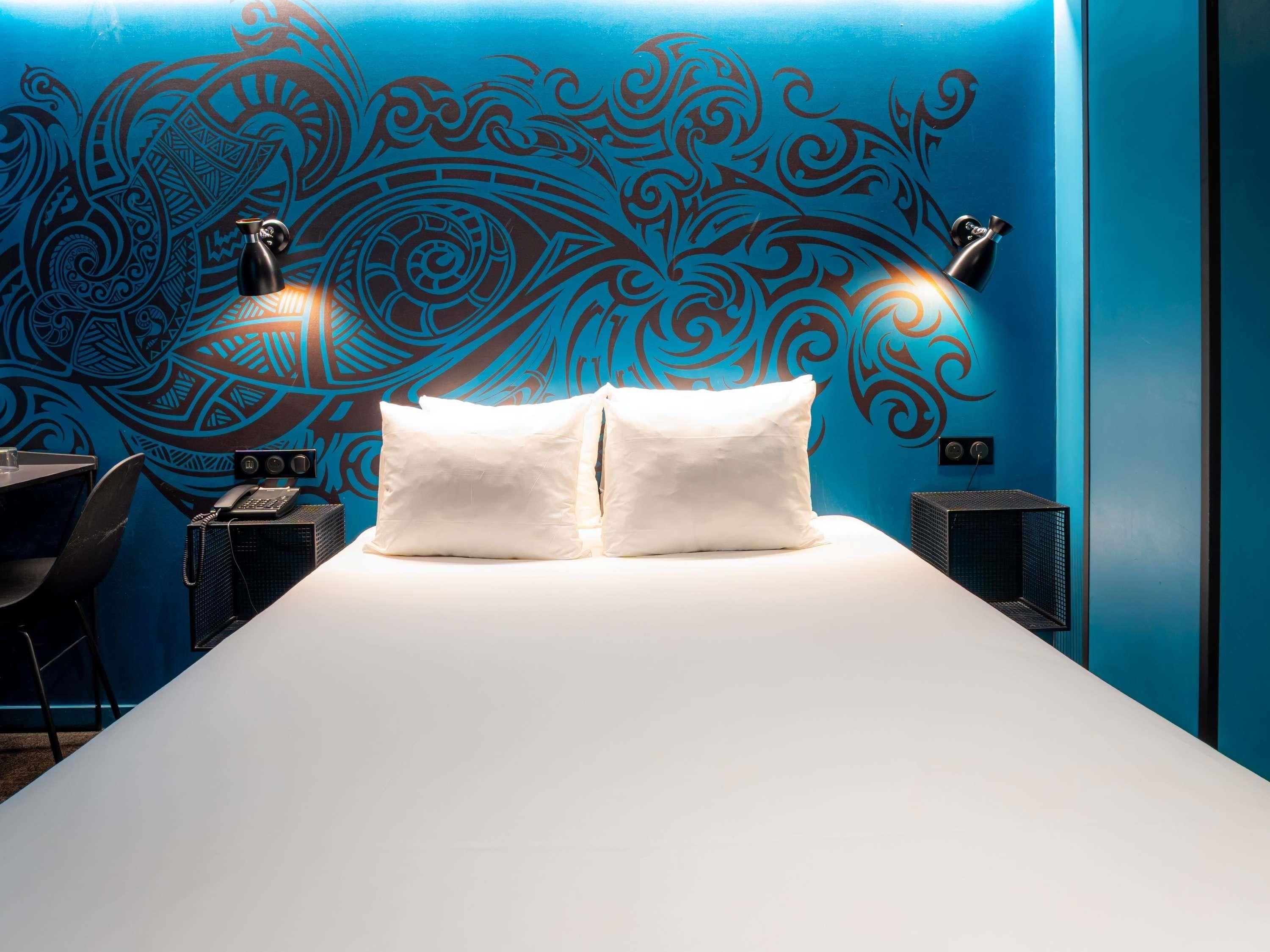 Ein Hotelzimmer mit einem großen Bett, zwei Nachttischlampen, einem Telefon und einer Wanddekoration.