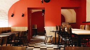 Un restaurante con piso a cuadros, paredes rojas y muebles de madera.