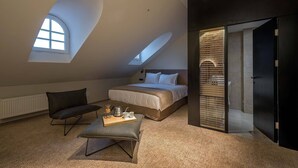 Un dormitorio moderno con una cama grande, una zona de estar con una mesita de centro y un tragaluz.